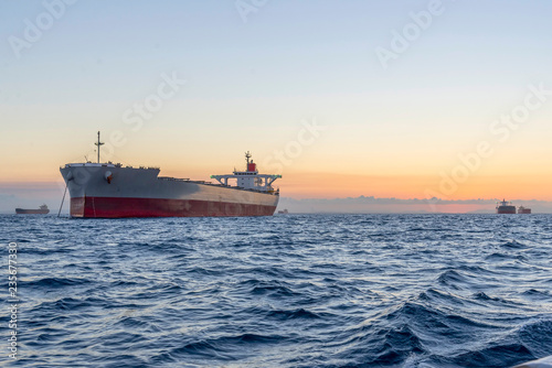 huge ships at sea at sunset with orange sky bacjground