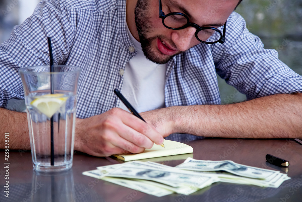 Successful businessman calculates profit and loss and makes note on paper.