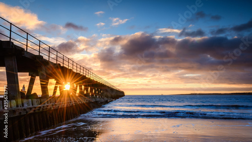 Fototapeta Naklejka Na Ścianę i Meble -  Sunburst on River Blyth Harbour West Pier, as the river reaches the North Sea between the piers in Northumberland