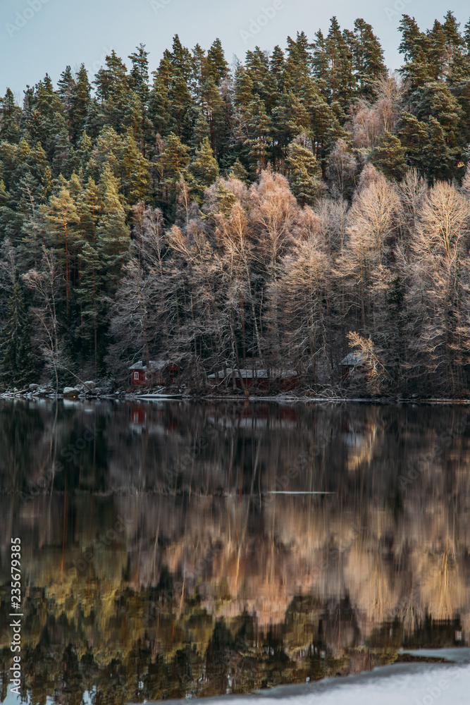 Incredible reflections in the lake with beautiful sunset light. The first frosts in Scandinavia, Finland