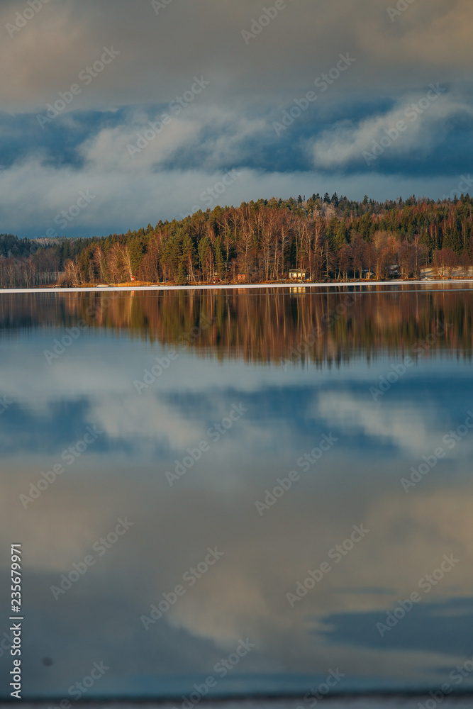 Obraz premium Incredible reflections in the lake with beautiful sunset light. The first frosts in Scandinavia, Finland