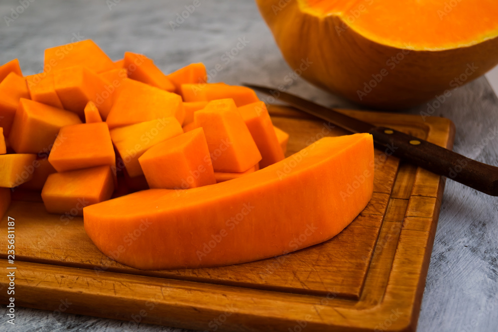 Cooking pumpkin. Cutting into pieces of ripe flesh. Kitchen cutting Board. Vegetarian food. Raw vegetables.