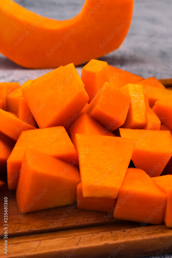 Pieces of sliced pumpkin on the kitchen Board. Preparation of raw vegetables. Vegetarian food. Orange flesh of ripe fruit.