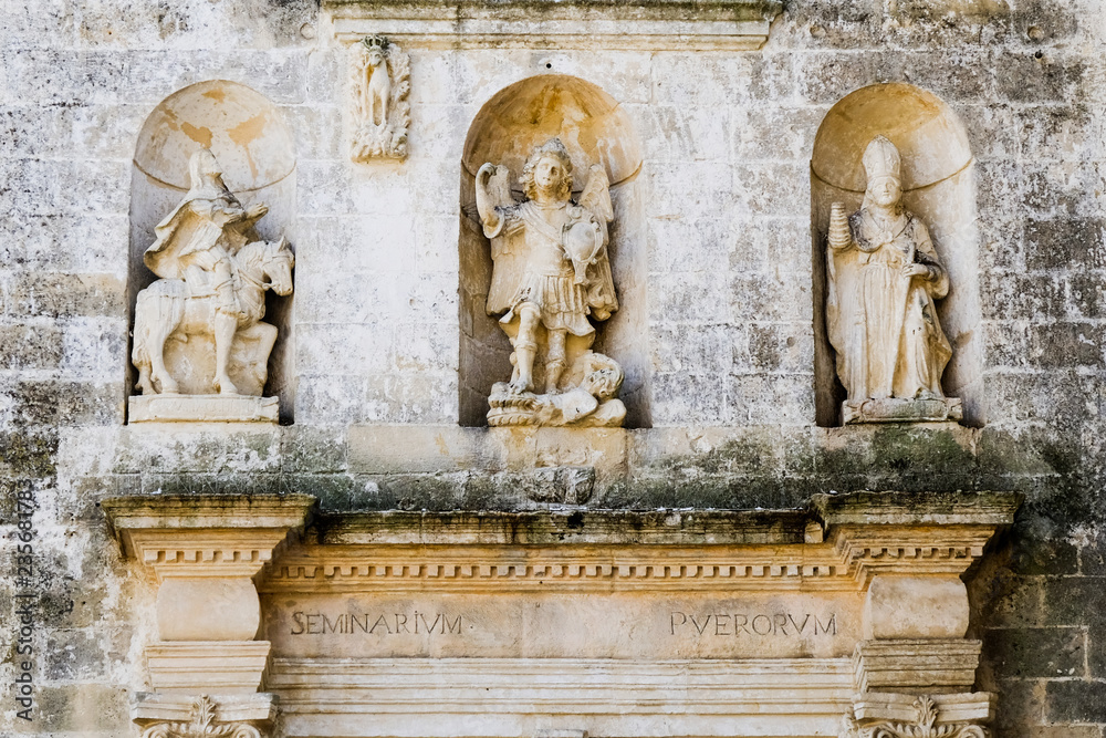 Sassi di Matera. Medieval sculptural group of three figures on the pediment of the seminary building.