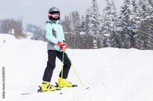 Teenage girl in helmet on the slope at ski resort