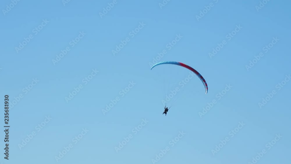 Tourist with instructor hovering in the sky on a paraglider. Tourist attraction over Rose Peak cable car road station. Rosa Khutor, Russia. Tourist with instructor hovering in the sky on a paraglider. Tourist attraction over Rose Peak cable car road station. Rosa Khutor, Russia.