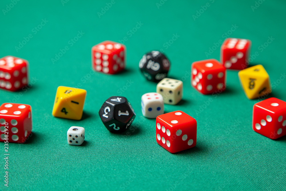 Collection of colored gaming dice cubes on green table Collection of colored gaming dice cubes on green table
