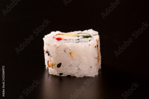 Japanese cuisine. One peace of sushi roll isolated on black background Closeup shot