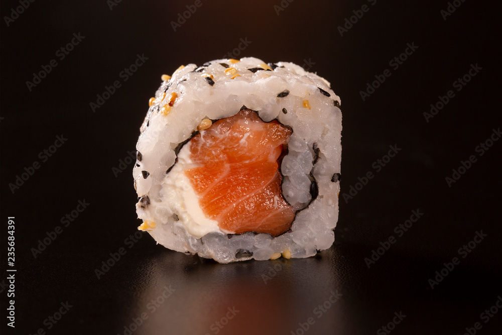 Japanese cuisine. One peace of sushi roll isolated on black background Closeup shot Japanese cuisine. One peace of sushi roll isolated on black background Closeup shot