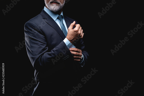 Quadro su tela elegant mature fashion man looking at his cufflinks while fixing them