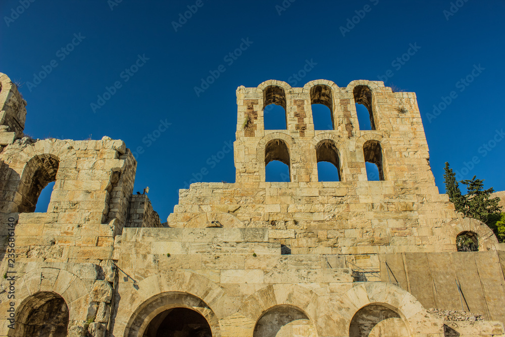 old ancient fortress ruins of stone wall with arch shape windows on empty blue sky background, copy space