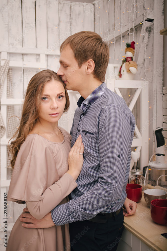 Young happy couple in love hugging.Young man and woman celebrate Christmas holidays together in a bright kitchen decorated for xmas. Merry Christmas and Happy New Year 2019 Holidays concept Young happy couple in love hugging.Young man and woman celebrate Christmas holidays together in a bright kitchen decorated for xmas. Merry Christmas and Happy New Year 2019 Holidays concept