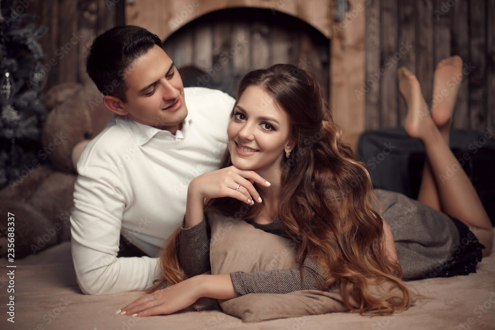 Young happy couple in love lying on rug in cozy wooden interior. Beautiful brunette woman with boyfriend enjoying. Young happy couple in love lying on rug in cozy wooden interior. Beautiful brunette woman with boyfriend enjoying.