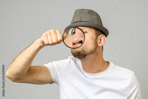 Astonished man looking through a magnifying glass