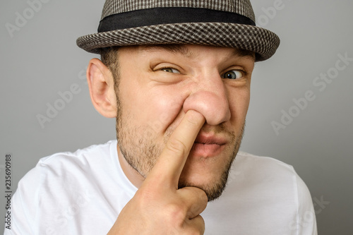 Foto Man picking his nose on gray background