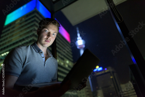 Photography Young handsome man using laptop against glass window with view o