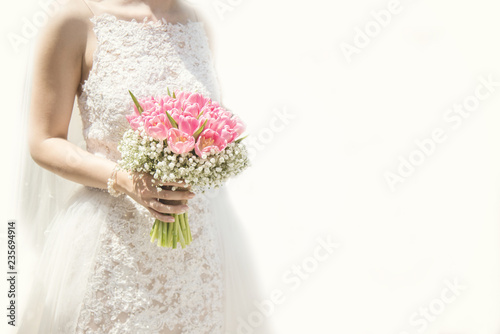 Beautiful bride in a wedding dress holding a bouquet of pink tulips. White background. Text space.