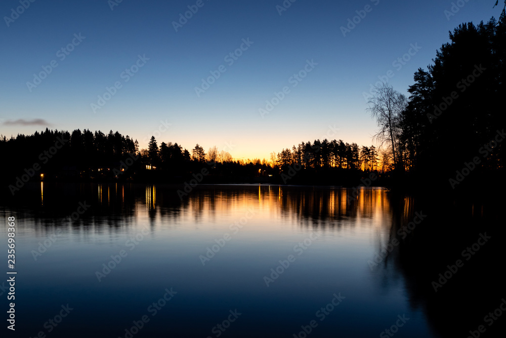 reflection of trees in water at sunrise