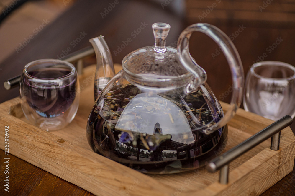 Purple floral herbal tea is poured from the brewer into the cup. Purple floral herbal tea is poured from the brewer into the cup.