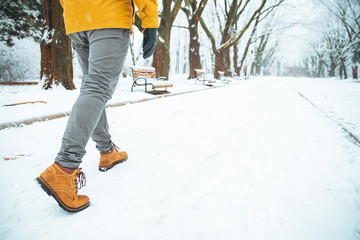 man walking by snowed winter city park legs close up concept