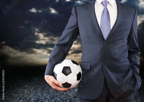 Young business man in grey suit holding football ball © BillionPhotos.com