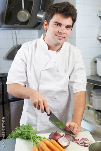 Portrait Of Chef Preparing Vegetables In Restaurant Kitchen
