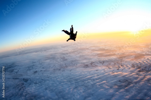 Tandem skydiving, flying above the Earth during sunset.