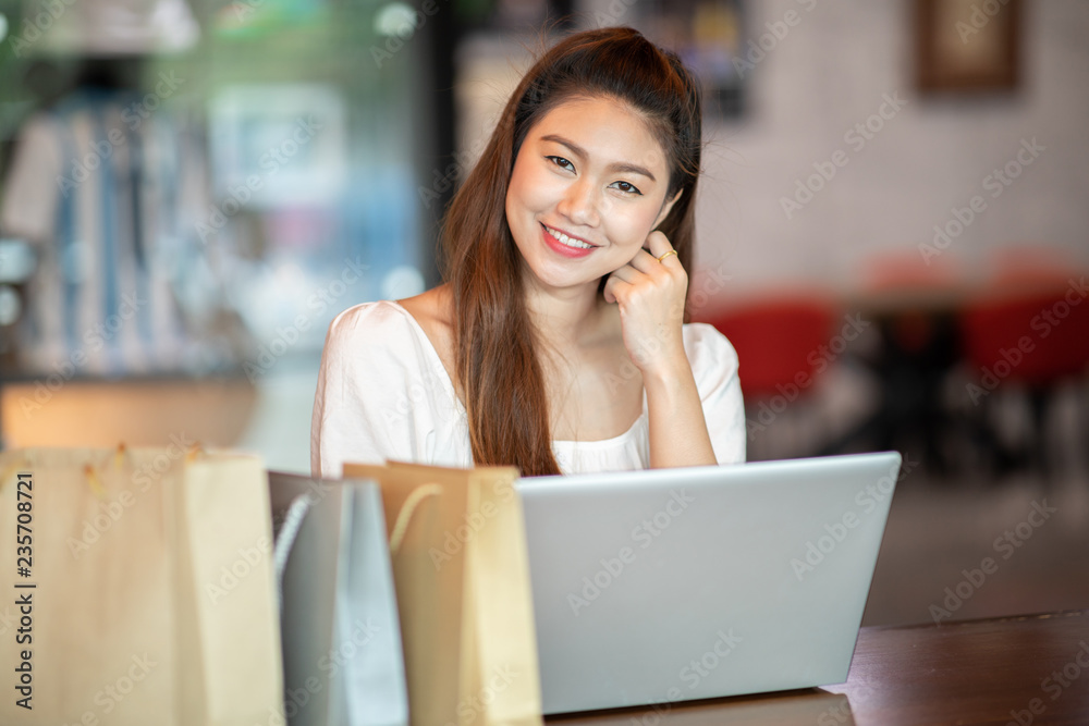 Beautiful Attractive Asian woman using computer laptop shopping online with shopping bags inside feeling so enjoy and happiness,Shopping online Concept