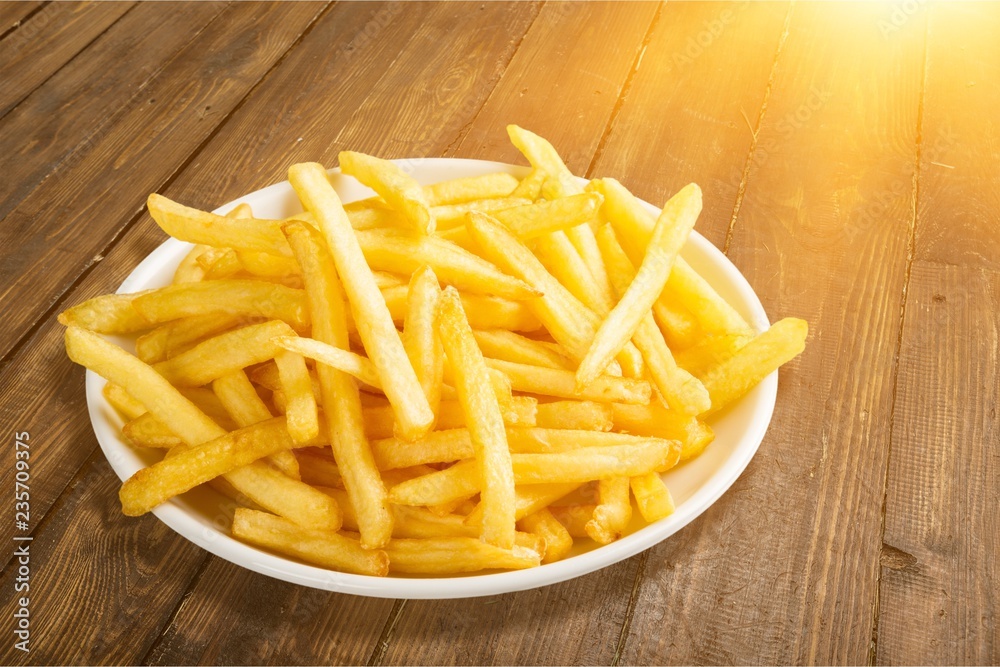 Plate of french fries on wooden table Plate of french fries on wooden table