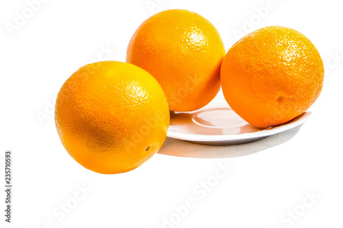 a three ripe oranges on plate on white background