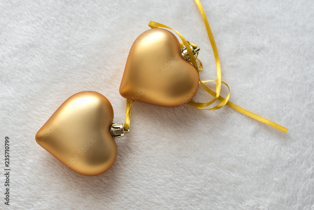 Christmas still life with love for loved ones, two golden hearts on one gold ribbon on a light background. Valentine's Day Gift