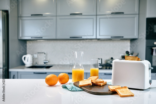 Portion of toasts on a wooden board with orange juice. Breakfast is served on a table with light blue napkin.