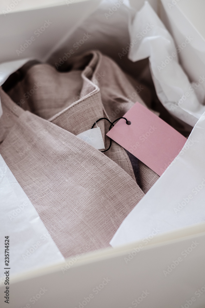 White opened box with wrapping paper and pink linen cloth and label. Copyspace for text White opened box with wrapping paper and pink linen cloth and label. Copyspace for text