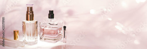Different perfume bottles and sampler on a pink floral background. Perfumery collection, cosmetics Banner photo