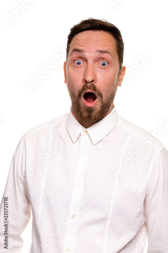 Unbelievable news. Young adult crazy man with opened mouth looking at camera. Studio shot, white background