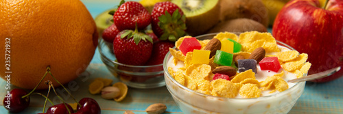 Tasty cornflakes with milk and fruits in glass bowl