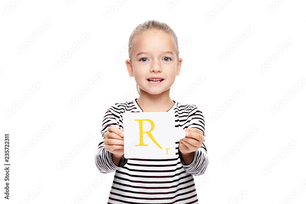 Young girl holding a card with letter R. Speech therapy concept on white background. Correct pronounciation and articulation at preschool age. - obrazy, fototapety, plakaty 
