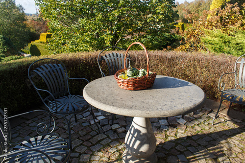 garden furniture, stone table with a basket with decorative pumpkins.