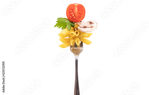 A fork with pasta on it. Tube form. A cherry tomato, a champignon and greenery photo