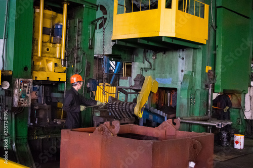 Hot iron in smeltery held by a worker. High precision hot forging product, automotive part production by hot forging process, automatice line hot forging. iron melting recycling work.