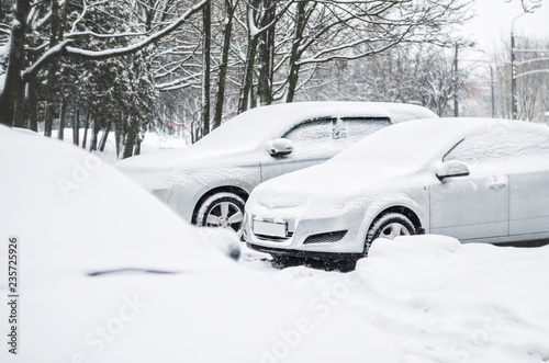 Cars in the parking lot are covered with a thick layer of snow. Concept: winter weather and car owner confrontation