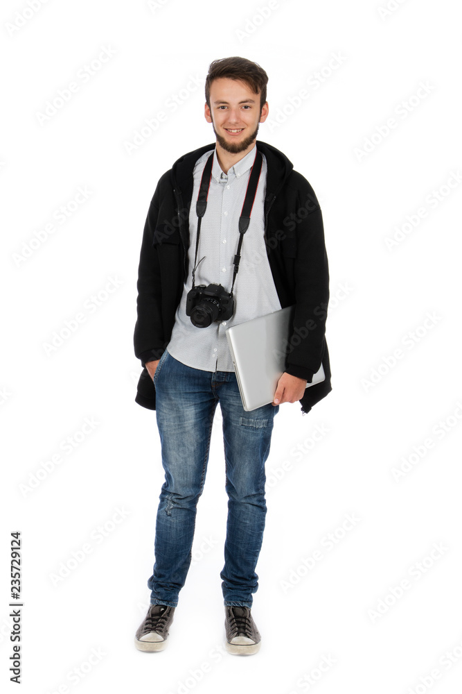 Nerd boy with camera around his neck and computer under his arm, he is standing in the studio and is wearing casual clothes Nerd boy with camera around his neck and computer under his arm, he is standing in the studio and is wearing casual clothes