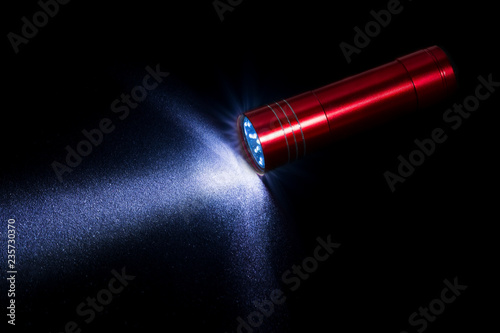 Flashlight on black background with visible beam of light