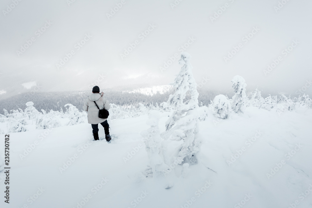 Alone photographer on mountain top in snowstorm with a backpack in winter time. Travel concept. Carpathian mountains. Landscape photography