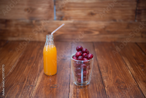 Sweet cherry, black cherries in a glass on wooden background with fresh juicy in glass bottle photo