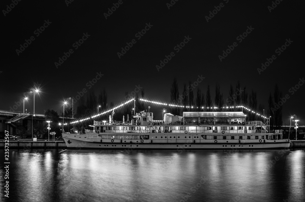 NIGHT CITY - An old stylish cruise ship by the river bank in Szczecin
