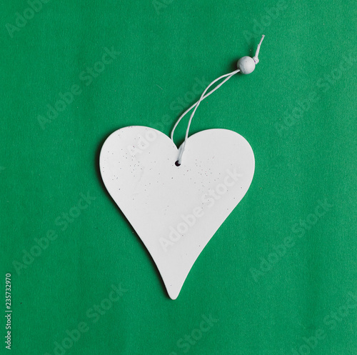 White heart shape toy with copy space isolated on green background.
