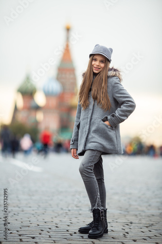 Photo of girl in gray hat and coat on blurred background at city