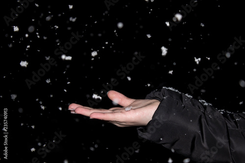 Women's hands catch falling snowflakes, dark time