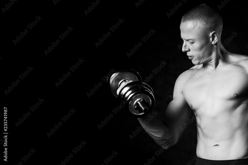 Handsome, muscular man with dumbbell.Black and white photo